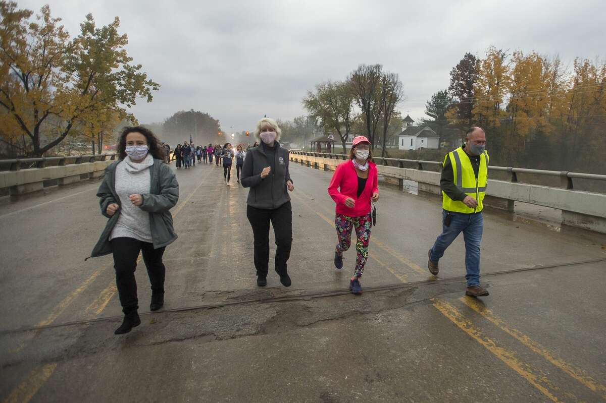From left, Midland County Commissioner Jeannette Snyder, State Rep. Annette Glenn, Sanford Village President Dolores Porte and Malley Construction Owner Brad Malley jog across the newly reconstructed Saginaw Road Bridge as it is officially reopened for the first time after being destroyed due to the May dam failures and flooding, on Oct. 23, 2020 in Sanford. (Katy Kildee/kkildee@mdn.net)