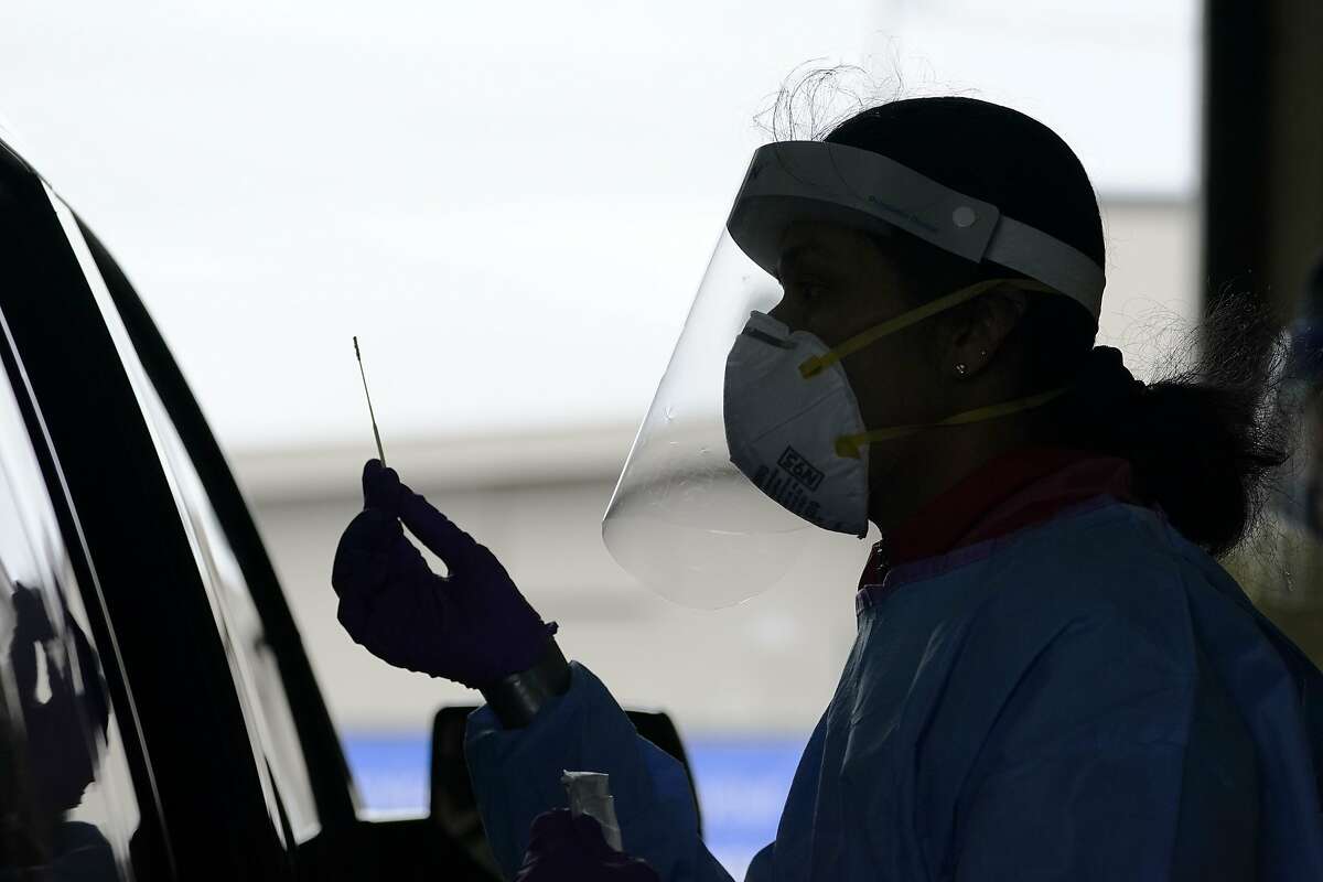 University of Washington research coordinator Rhoshni Prabhu holds up a swab after testing a passenger at a free COVID testing site Friday, Oct. 23, 2020, in Seattle. The United States is approaching a record for the number of new daily coronavirus cases in the latest ominous sign about the disease's grip on the nation, as states from Connecticut to Idaho reel under the surge. (AP Photo/Elaine Thompson)