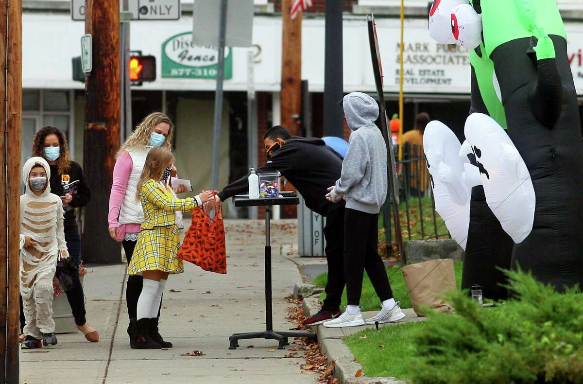 Local families wander through downtown Milford, Conn., taking part in a safe, socially distant way to enjoy the Halloween holiday on Saturday Oct. 24, 2020. Sponsored by Spinnaker Milford, participating shops put a scarecrow out front and offered treats to local kids.