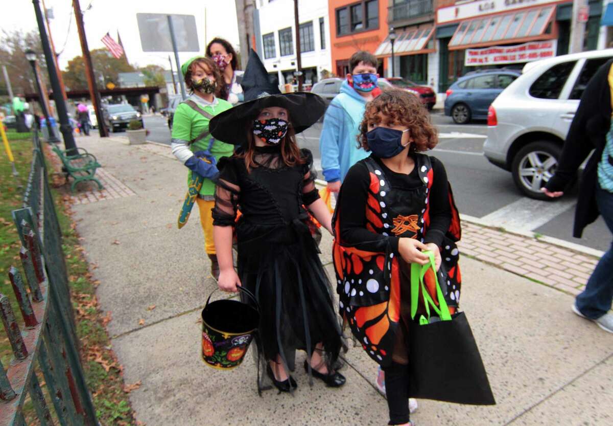 Local families wander through downtown Milford, Conn., taking part in a safe, socially distant way to enjoy the Halloween holiday on Saturday Oct. 24, 2020. Sponsored by Spinnaker Milford, participating shops put a scarecrow out front and offered treats to local kids.
