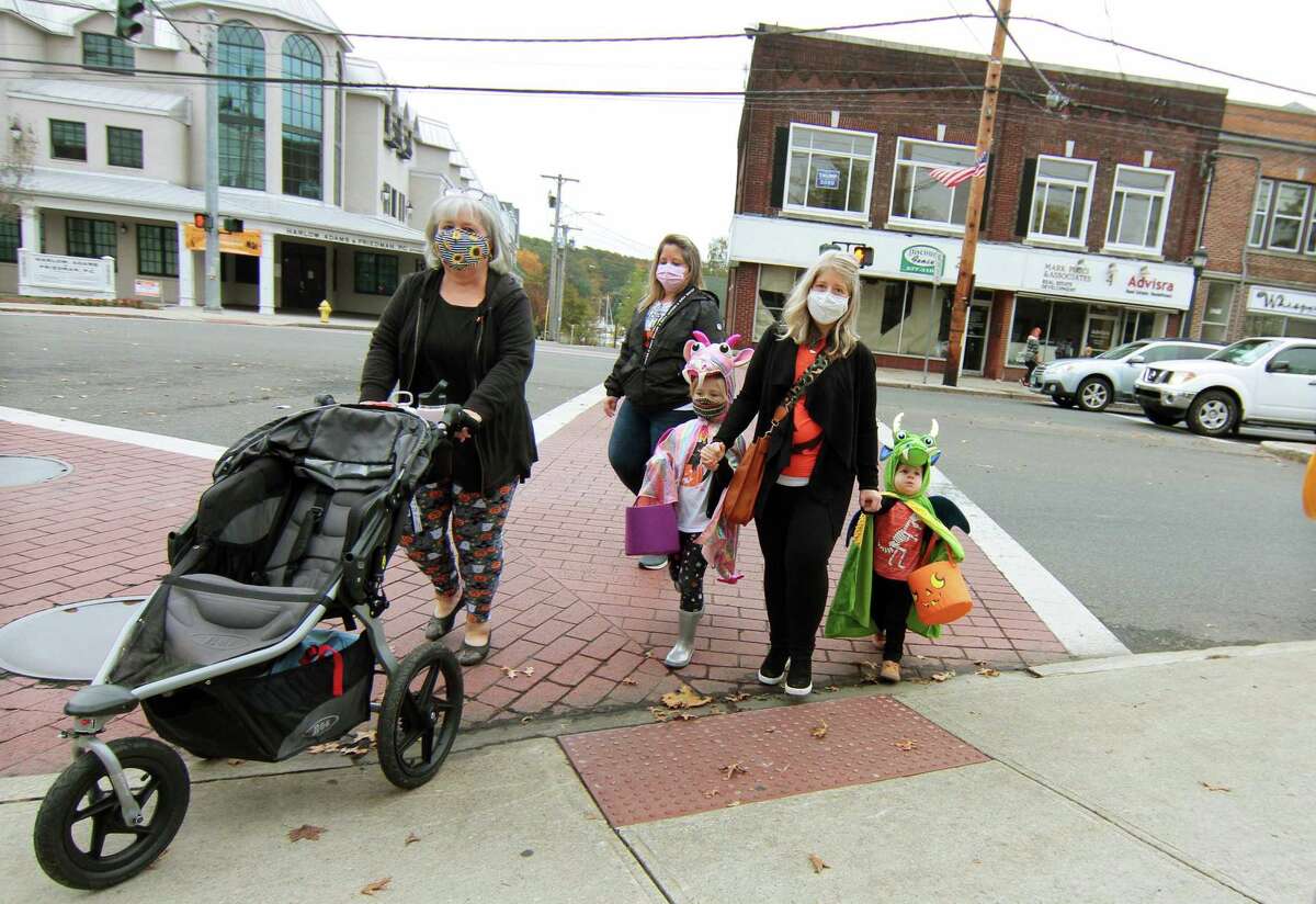 Local families wander through downtown Milford, Conn., taking part in a safe, socially distant way to enjoy the Halloween holiday on Saturday Oct. 24, 2020. Sponsored by Spinnaker Milford, participating shops put a scarecrow out front and offered treats to local kids.