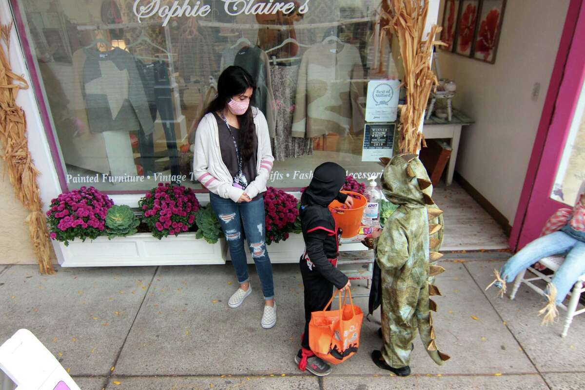 Local families wander through downtown Milford, Conn., taking part in a safe, socially distant way to enjoy the Halloween holiday on Saturday Oct. 24, 2020. Sponsored by Spinnaker Milford, participating shops put a scarecrow out front and offered treats to local kids.