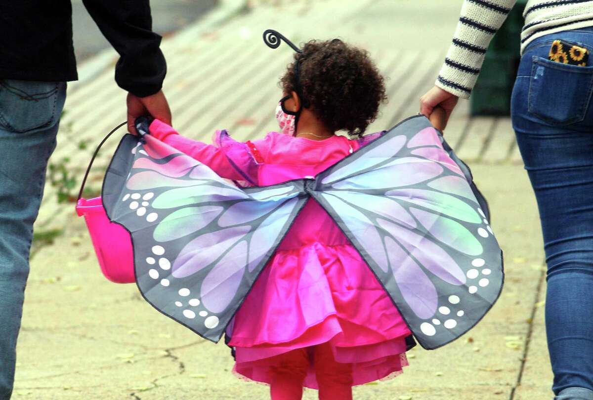 Local families wander through downtown Milford, Conn., taking part in a safe, socially distant way to enjoy the Halloween holiday on Saturday Oct. 24, 2020. Sponsored by Spinnaker Milford, participating shops put a scarecrow out front and offered treats to local kids.