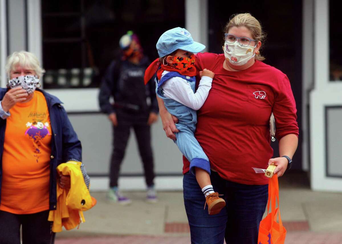 Leo Hicks, 3, of Milford, his mom Brittany and grandmother Lucinda, left, take part in a safe, socially distant way to enjoy the Halloween holiday in downtown Milford, Conn., on Saturday Oct. 24, 2020. Sponsored by Spinnaker Milford, participating shops put a scarecrow out front and offered treats to local kids.