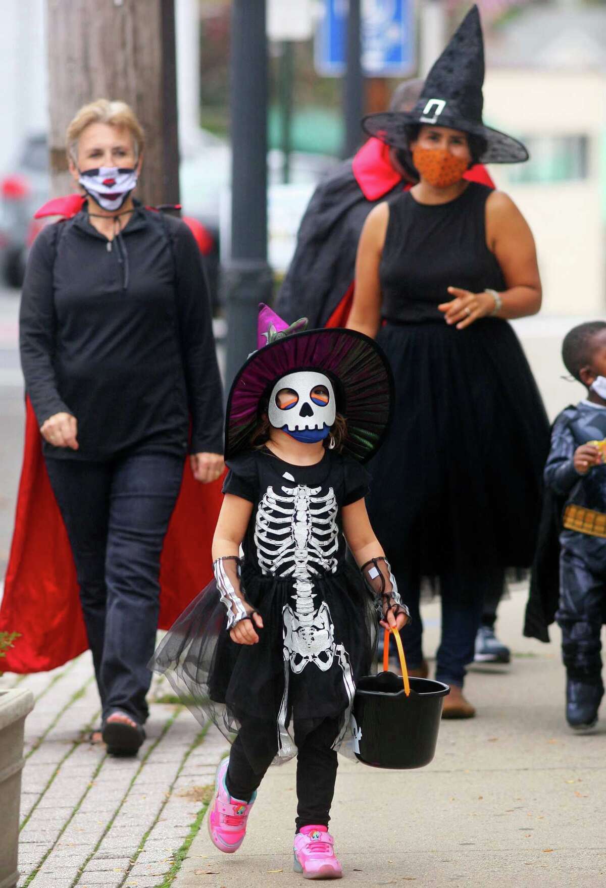 Olive McConnell, 5, of Milford,walks with her family through downtown Milford, Conn., taking part in a safe, socially distant way to enjoy the Halloween holiday on Saturday Oct. 24, 2020. Sponsored by Spinnaker Milford, participating shops put a scarecrow out front and offered treats to local kids.