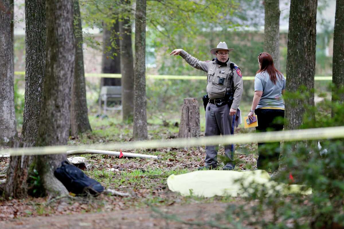 A state trooper and forensics investigator walk through the debris field at the site of a a plane crash Sunday, Oct. 25, 2020 in Woodbranch, TX. Initial reports are two are dead. The plane crashed in residential area in a wooded patch between three homes, each approximately 50 yards away from the wreckage.
