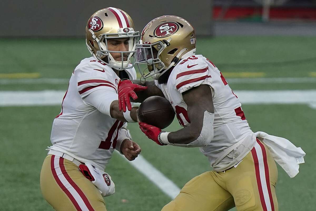 Above: 49ers quarterback Jimmy Garoppolo (left) hands off to running back Jeff Wilson, who ran for 112 yards and three touchdowns against New England. Below: Wilson was carted off the field after he suffered an ankle injury in the third quarter.