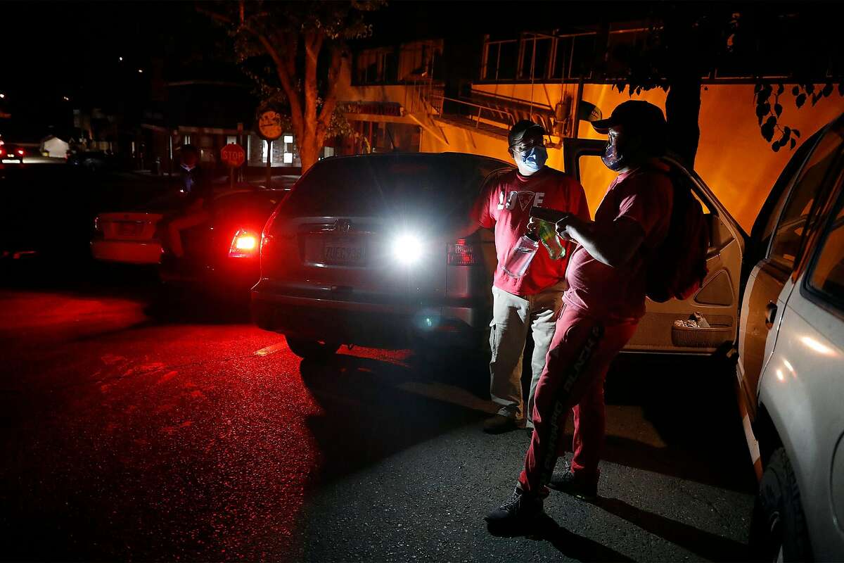 Mountain Mike Pizza employees David Woodman and Liam Carrington (right) chat on LaSalle Avenue during PG&E Public Safety Power Shutoff in Montclair neighborhood of Oakland, Calif., on Sunday, October 25, 2020. The pizza place closed early due to the PSPS that started at 8:45pm.
