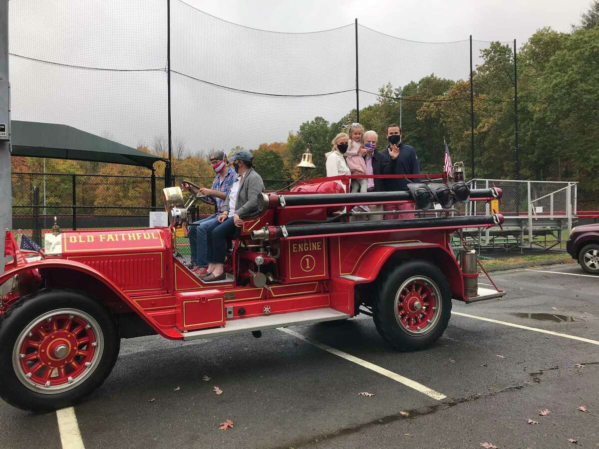 Tom Stadler holds his granddaughter, Kate, in the back of an Old Faithful antique fire engine, flanked by his wife, Jan, and son, Sean, in Mead Park Friday, Oct. 23, when a party was held in honor of his retirement.