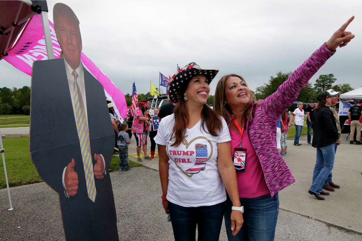 Emily McHattie, left, and Marri Velasguez, right, stand next to a life size Donald Trump cutout as they and other Trump supporters gather at the Montgomery County Constable offices parking lot before the start of the “Magnolia Trump Train Parade” Saturday, Oct. 17, 2020 in Magnolia, TX.