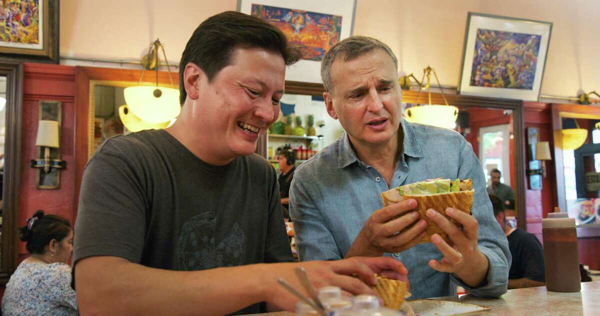 Phil Rosenthal, right, host of Netflix's "Somebody Feed Phil," eats a sandwich in San Francisco.