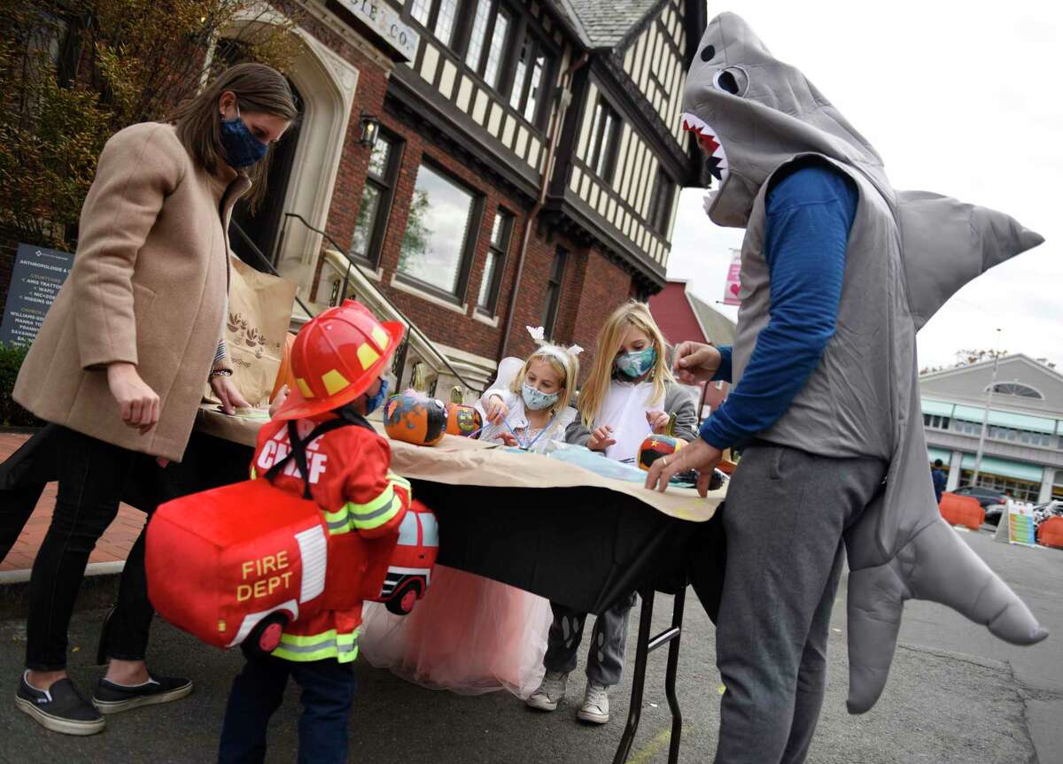 Kate and Augie Wilkinson and their children Jack, 3, Melody, 5, and Emma, 7, paint pumpkins at the Westport Downtown Merchants Association Halloween Family Pumpkinfest in Westport, Conn. Sunday, Oct. 25, 2020. 150 families dressed in Halloween costumes participated in the socially-distant pumpkin painting event, presented by the Westport Parks & Recreation and Westport Police Athletic League in partnership with the WDMA.