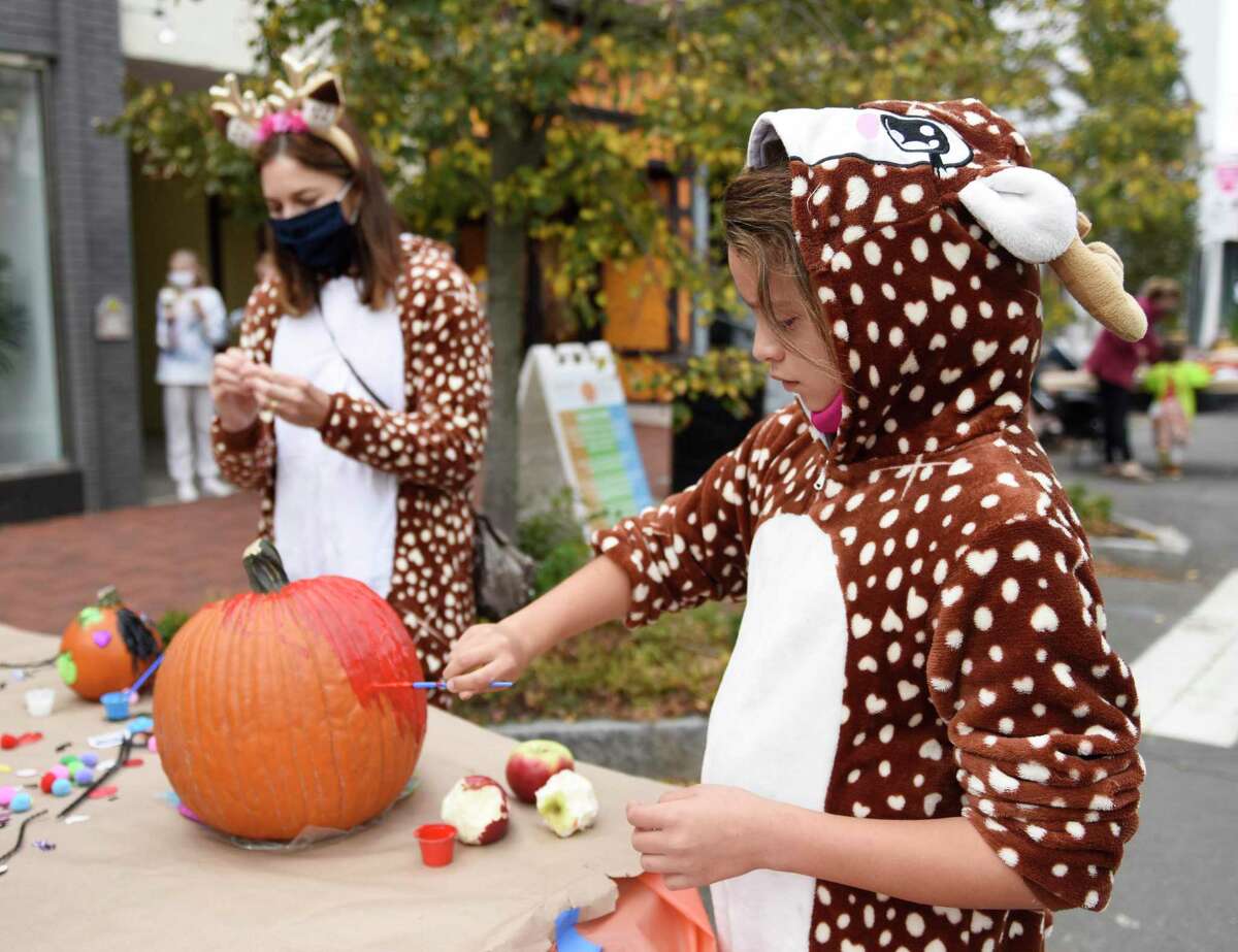 Westport's Zoey Zografos, 9, paints pumpkins with her family at the Westport Downtown Merchants Association Halloween Family Pumpkinfest in Westport, Conn. Sunday, Oct. 25, 2020. 150 families dressed in Halloween costumes participated in the socially-distant pumpkin painting event, presented by the Westport Parks & Recreation and Westport Police Athletic League in partnership with the WDMA.