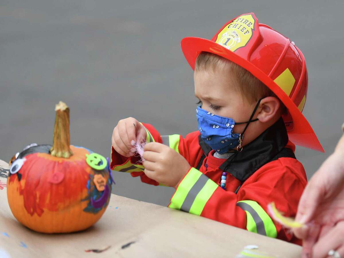 A boy decorates a pumpkin at the Westport Downtown Merchants Association Halloween Family Pumpkinfest in Westport, Conn. Sunday, Oct. 25, 2020. 150 families dressed in Halloween costumes participated in the socially-distant pumpkin painting event, presented by the Westport Parks & Recreation and Westport Police Athletic League in partnership with the WDMA.