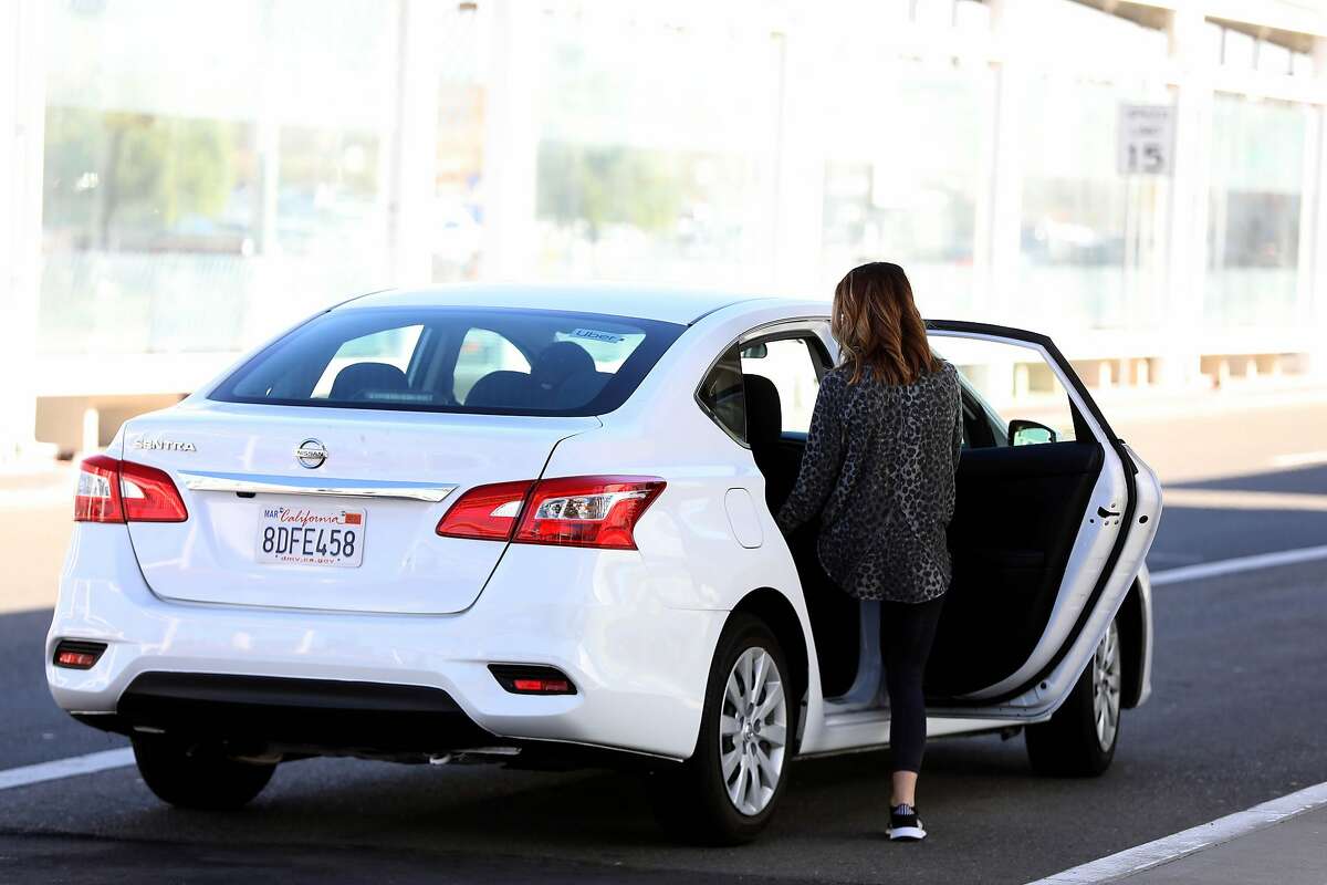 A passenger steps into an Uber car at the Oakland airport in October.