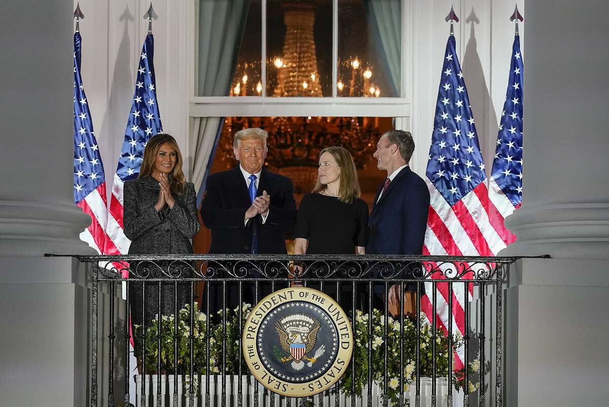 First lady Melania Trump and President Trump applaud new Supreme Court Justice Amy Coney Barrett as they stand with her and her husband, Jesse Barrett, on a White House balcony after her swearing in.