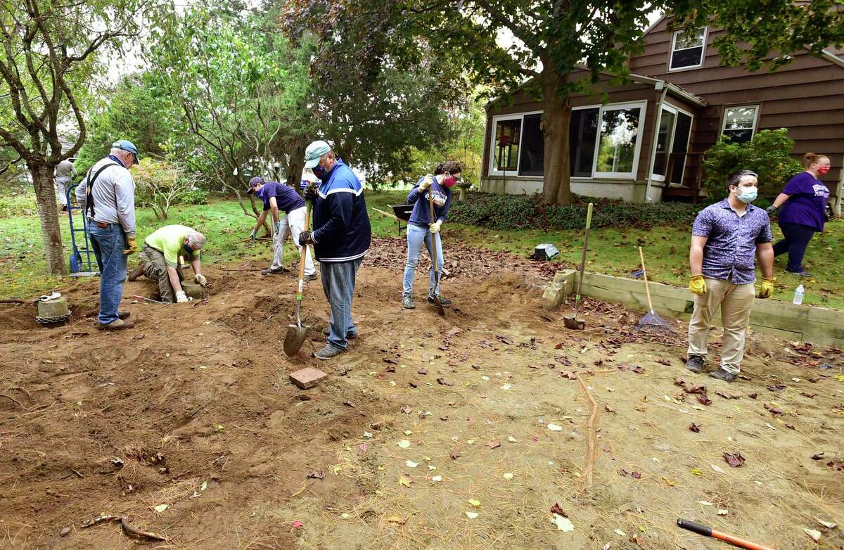 Volunteers with the Milford Land Conservation Trust cleanup a newly acquired 1.12 acre property at the end of Anchorage Drive Saturday.