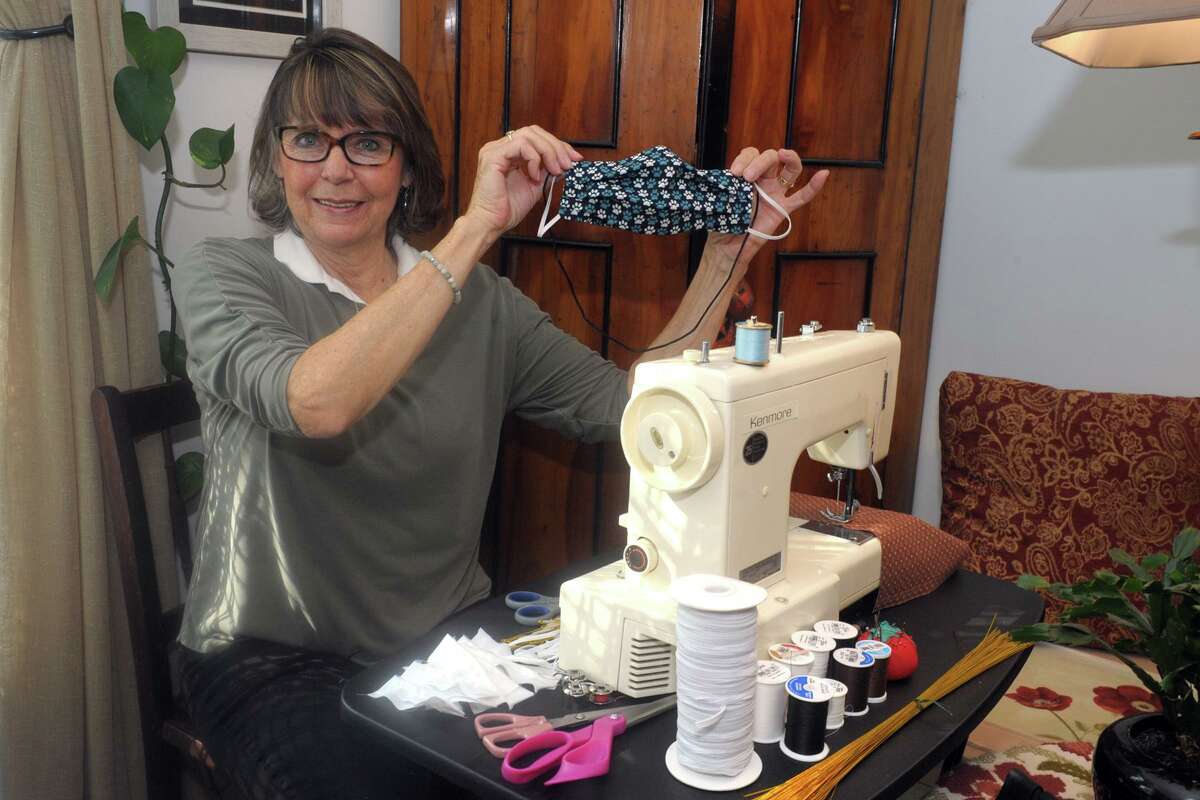 Barbara Long poses at her sewing machine with one of her homemade protective masks in Milford.
