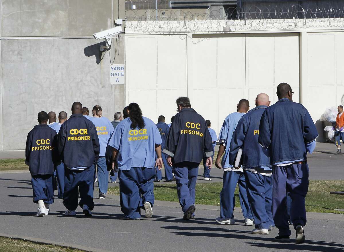 FILE - In this Feb. 26, 2013, file photo, inmates walk through the exercise yard at California State Prison Sacramento, near Folsom, Calif. In November 2020, California voters will consider rolling back a host of criminal justice changes in what amounts to a referendum on whether the famously progressive state has become too lenient. Proposition 20 would amend criminal sentencing and supervision laws enacted during the administration of Gov. Jerry Brown that critics say are too favorable to criminals, while Proposition 25 could overturn a 2018 law that eliminates cash bail. (AP Photo/Rich Pedroncelli, File)