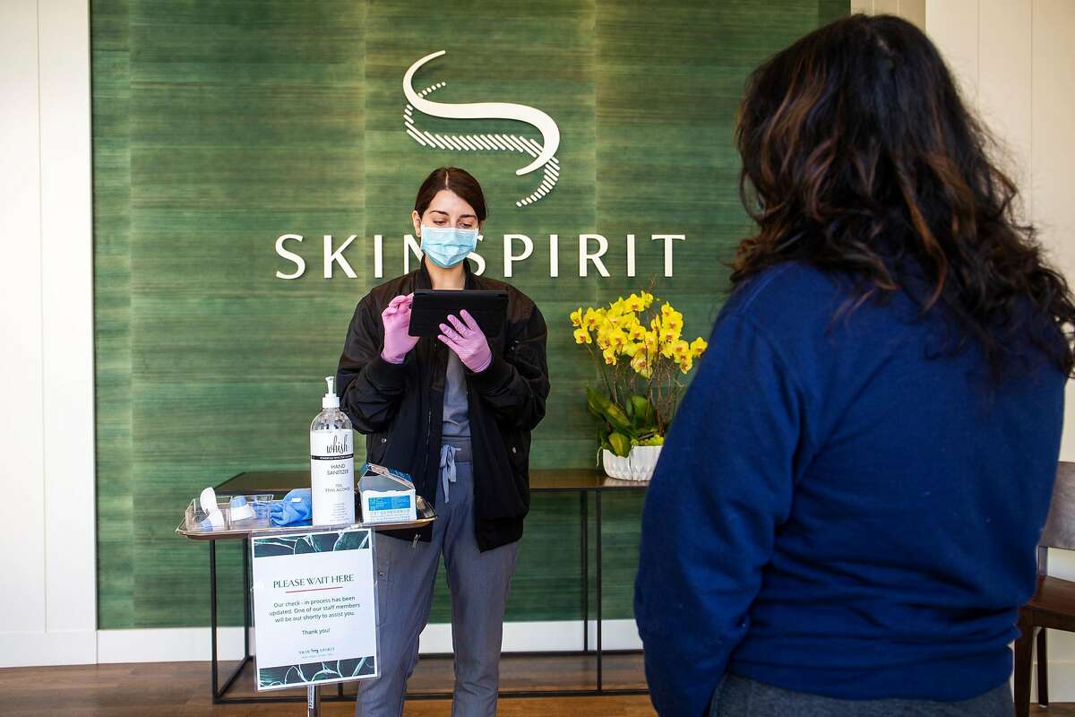 Tatiana Vilchez, an administrator at SkinSpirit, goes through a check-in with Sravanti Tekumalla, who recieved a facial on Tuesday, the first day that spas were allowed to offer certain services in San Francisco.
