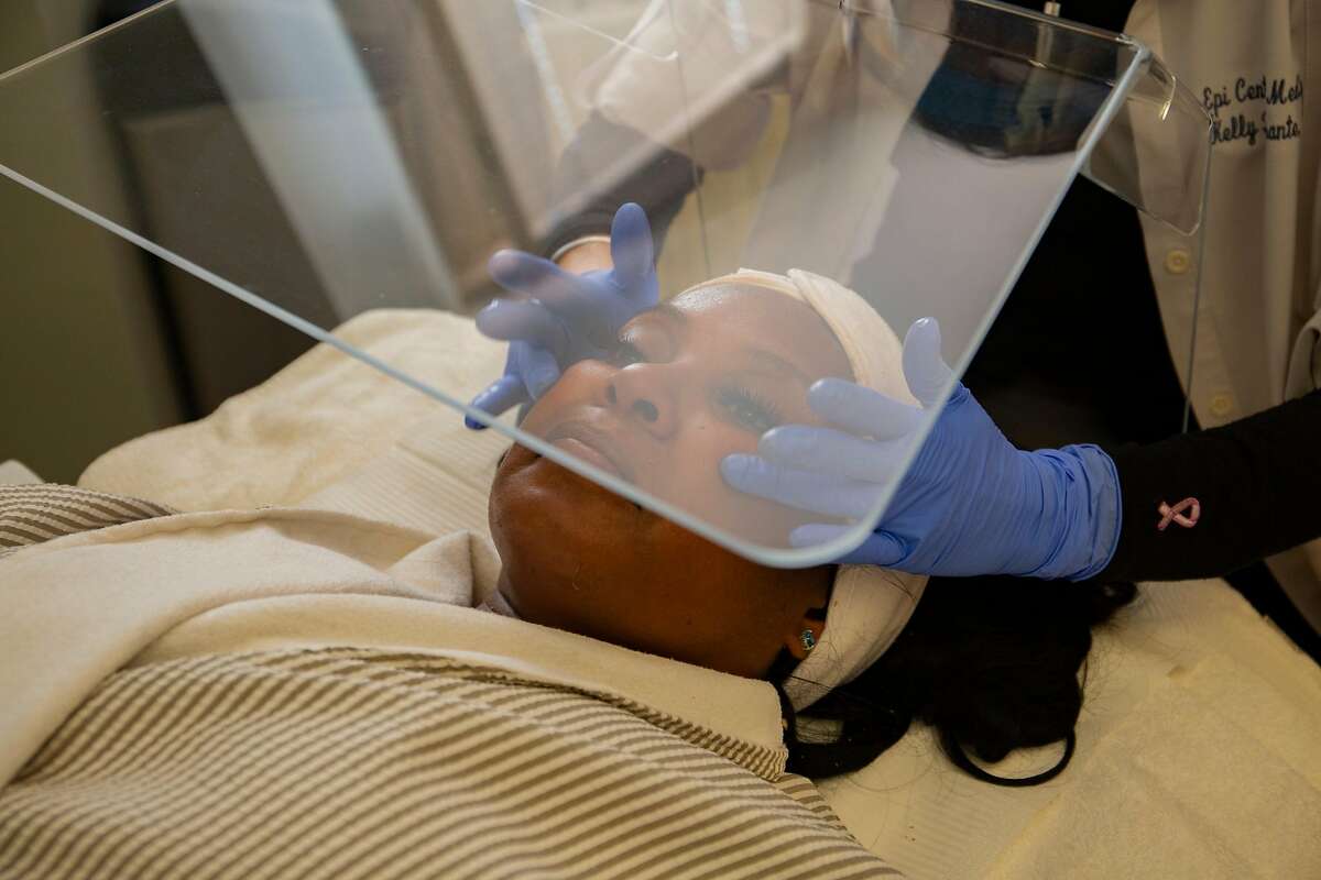 Chaundra Woods recieves her first facial in months from nurse Kelly Ferrante under a plexiglass barrier, on Tuesdayin downtown San Francisco.