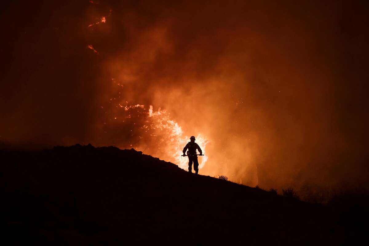 A firefighter fights the Blue Ridge Fire in Chino Hills, Calif., on Oct. 27, 2020. The Silverado Fire and the Blue Ridge Fire nearly doubled in size overnight, and have forced more evacuations in Irvine and other parts of Orange County.
