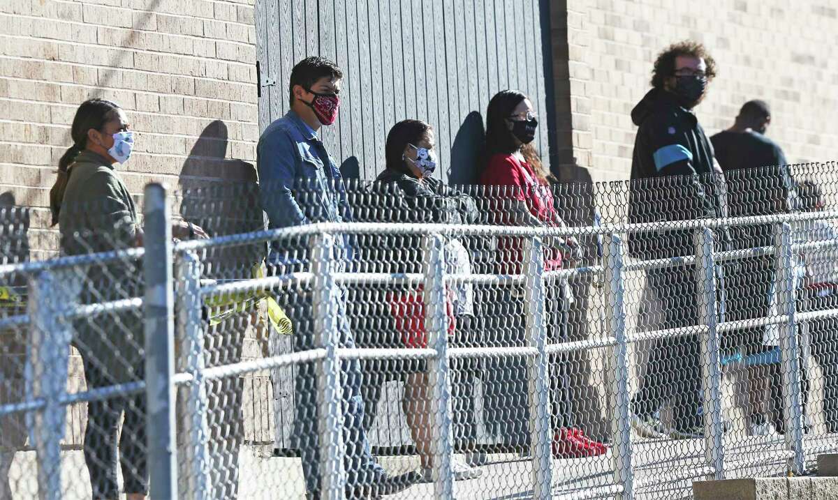 Everyone in line has a face covering at the Johnston Branch Library on Medina Base Road as voters wear masks while voting on the Southside on Oct. 28, 2020.