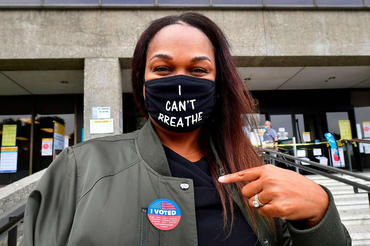 Tonya Swain points to her “I Voted” sticker after casting her vote in the Norwalk (Los Angeles County) on Oct. 19.