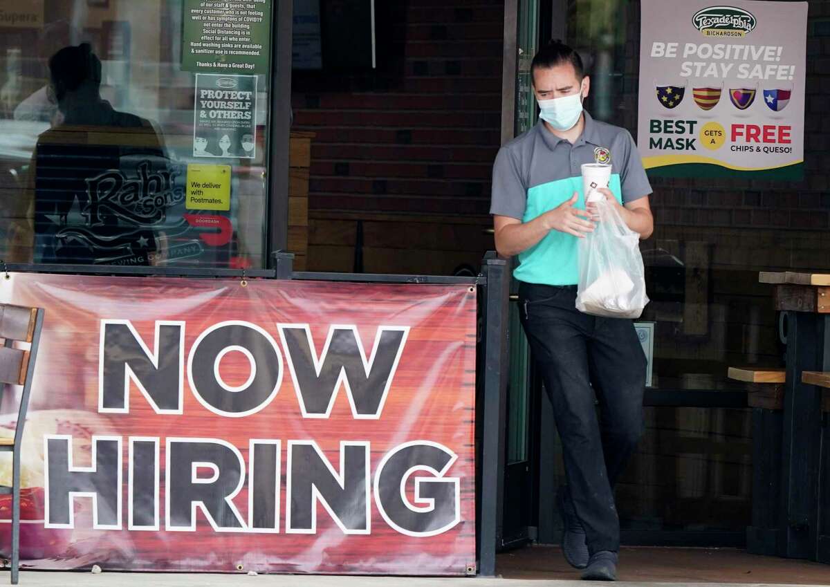 In this Sept. 2, 2020 file photo, a customer wears a face mask as they carry their order past a now hiring sign at an eatery in Richardson, Texas. 