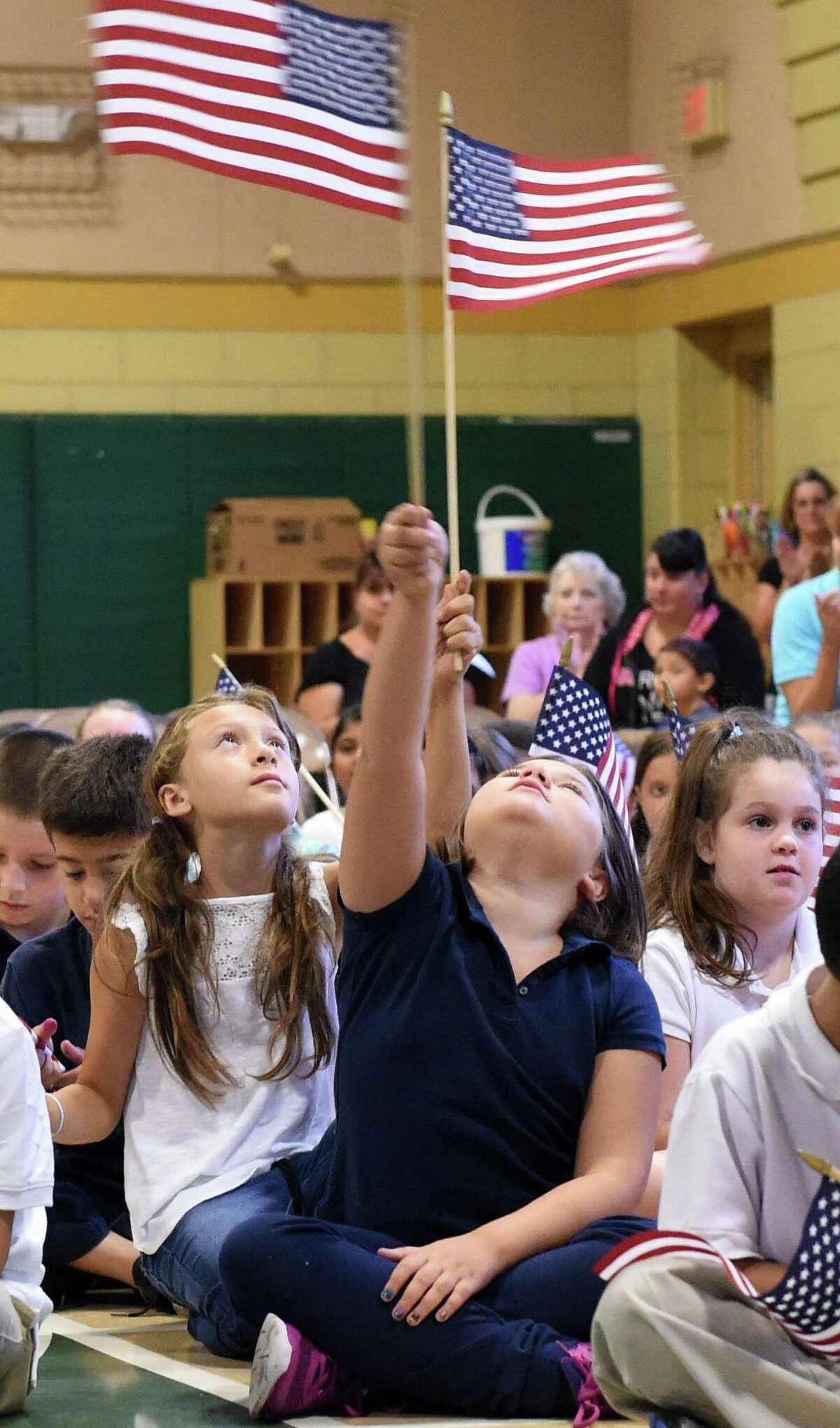 (Peter Hvizdak - New Haven Register) Two elementary school students raise the U.S. flag high during a during a We Love America Day school assembly honoring the memory of the heroes of the 9/11 in the gym at the Grove J. Tuttle Elementary School in East Haven, Connecticut Friday, September 11, 2015 marking the anniversary of the 9/11 attacks on the United States in 2001.
