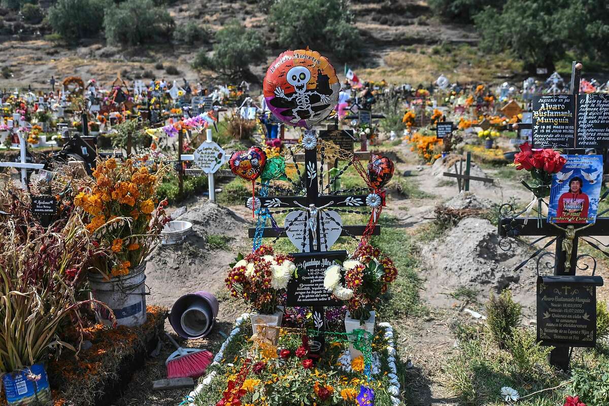 People decorate relatives’ graves prior to the traditional Nov. 1-2 Day of the Dead observances at a cemetery in Valle de Chalco, Mexico state. Many cemeteries to prevent the spread of the coronavirus.