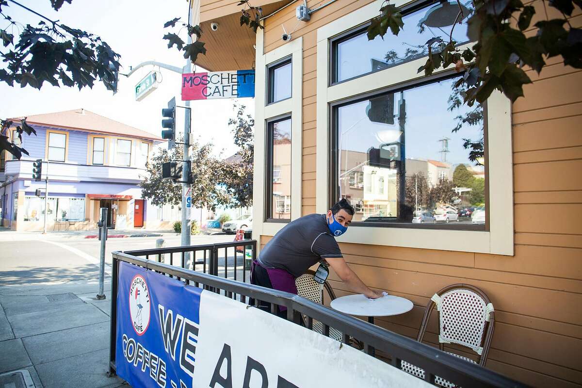 Sally Flores, an employee at Moschetti’s Cafe in Vallejo, sprays down tables before closing up for the day.