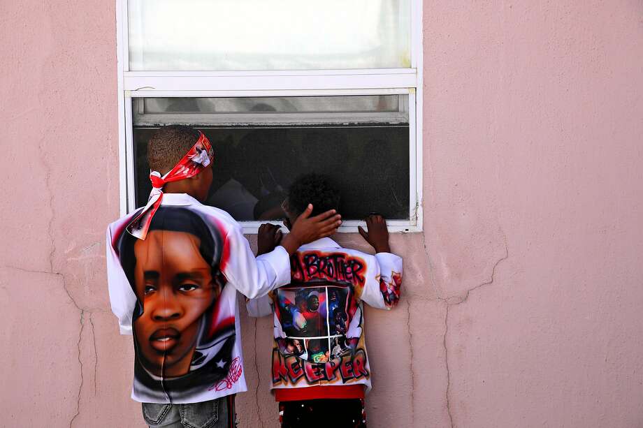 Trayvon Hall (left), 7, comforts his cousin, Kai Pryor, 4, as he peeks through a window during the funeral service for his older brother Aaron Pryor, a 16-year-old star athlete who was shot to death i near his home in September. Photo: Photos By Yalonda M. James / The Chronicle