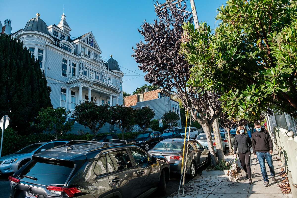 People walk along the sidewalk near the Nobby Clarke Mansion in San Francisco on Friday, October 30, 2020.