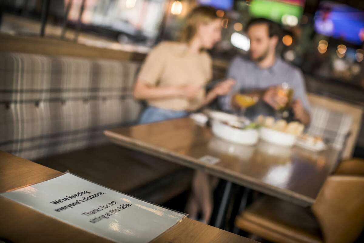 A sign reminds patrons to maintain physical distance from other diners at a restaurant.