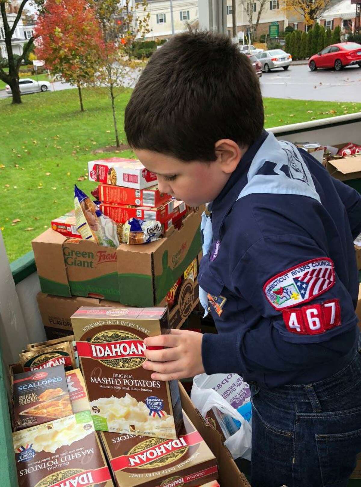 The Woman’s Club of Greater New Milford and the United Way of Western Connecticut will hold a food drive, “Operation Thanksgiving,” Nov. 7 near the bandstand on the Village Green. Above, Scout Nathan Brennen assists the group by checking expiration dates on donated goods during the 2018 event.
