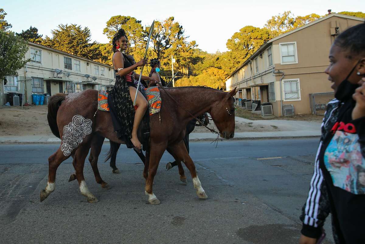 Brianna Noble (left) her friend Dale Johnson, and Noble’s sister, Brittany Lewis, ride their horses through the Sunnydale neighborhood clad in their “Black Panther”-inspired-costumes during a socially distanced Halloween event Friday.