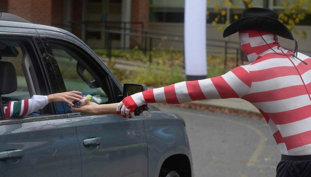 Kregg Zulkeski, from the Parks & Recreation department, hands out treats at the drive-thru Halloween event held at the Comstock Community Center on Friday afternoon, October 30, 2020, in Wilton, Conn.