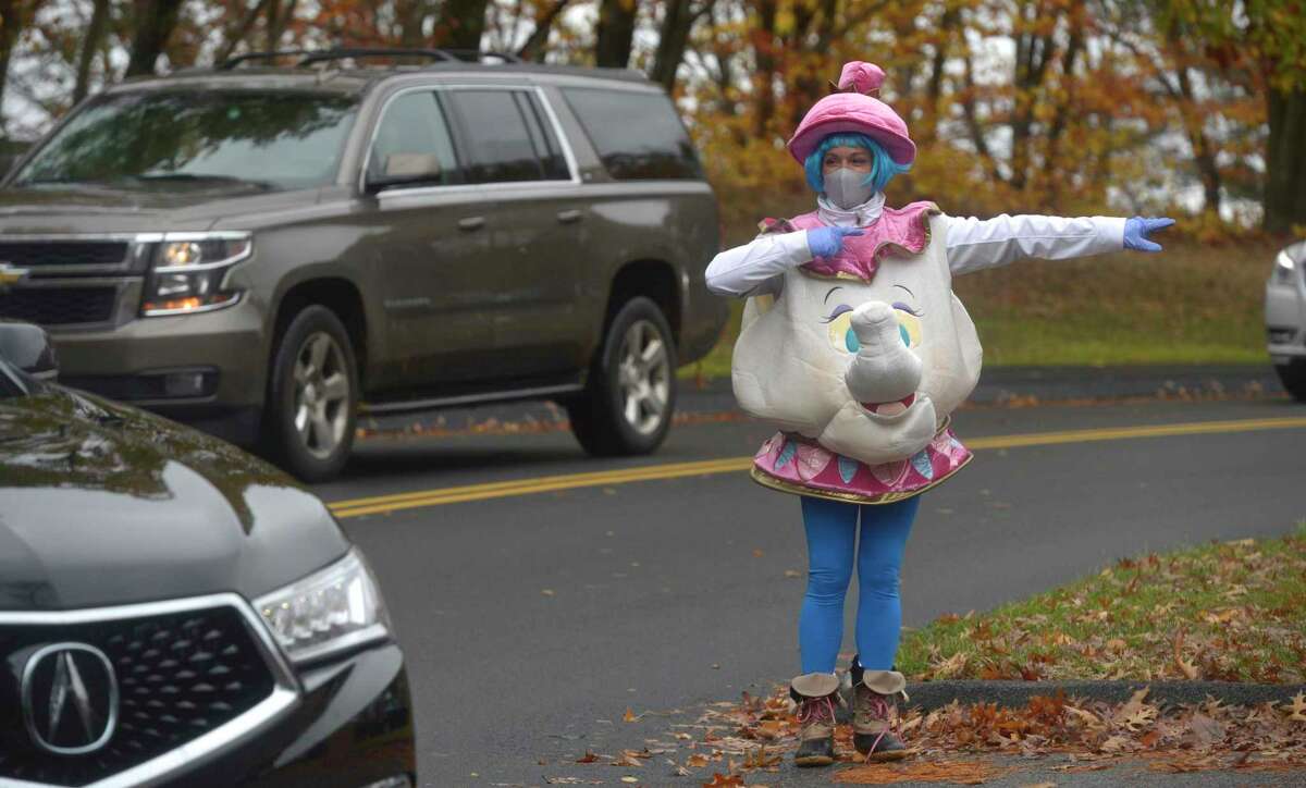 Tracy Loher, a volunteer, directs cars into the drive-thru Halloween event held at the Comstock Community Center on Friday afternoon, October 30, 2020, in Wilton, Conn.