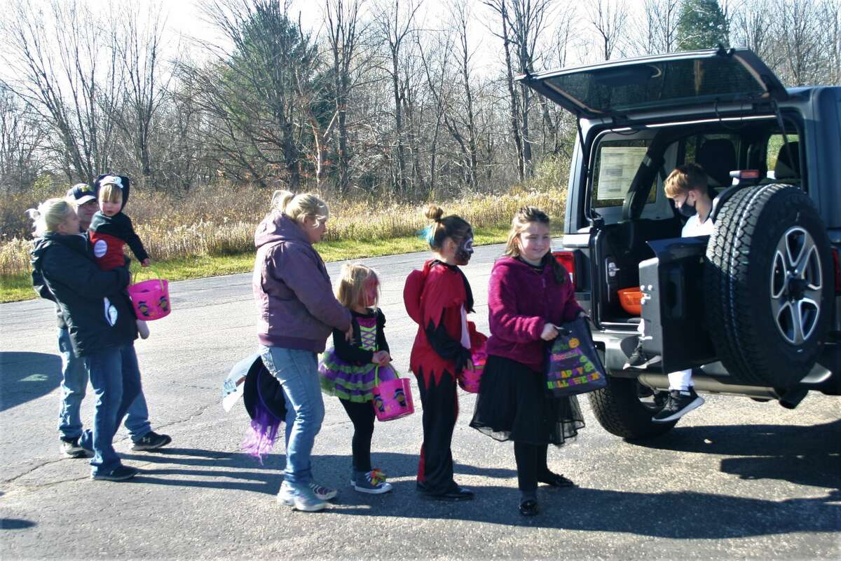 Children dressed in Halloween costumes collect treats as they participate in the Betten Baker Trunk-or-Treat on Saturday.