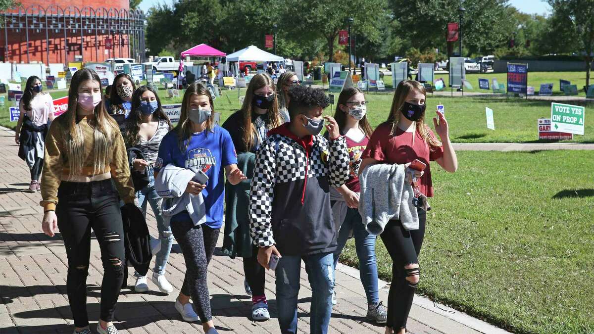 Students notice the electioneering as voters walk in to the polls on the campus of Texas State University on Oct. 30, 2020.