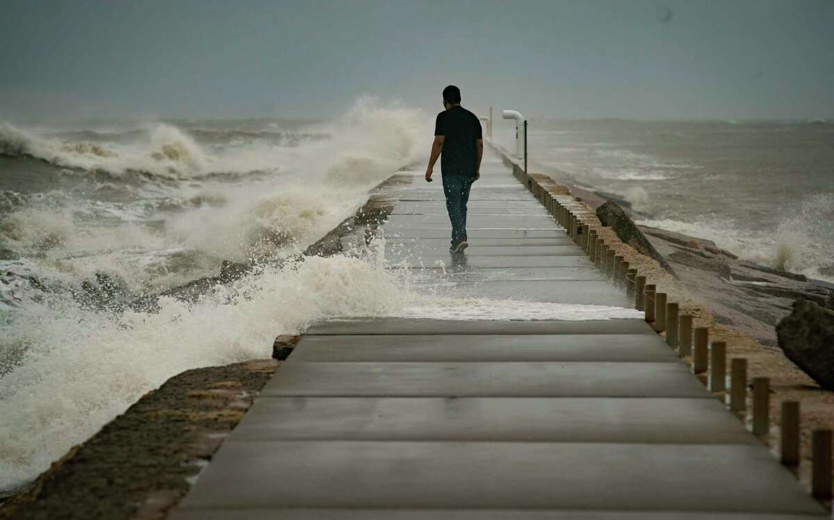 Naythan Lezama walks down the jetty at Surfside Beach, watching the waves as Hurricane Delta approaches the Louisiana coast to the east, Friday, Oct. 9, 2020.