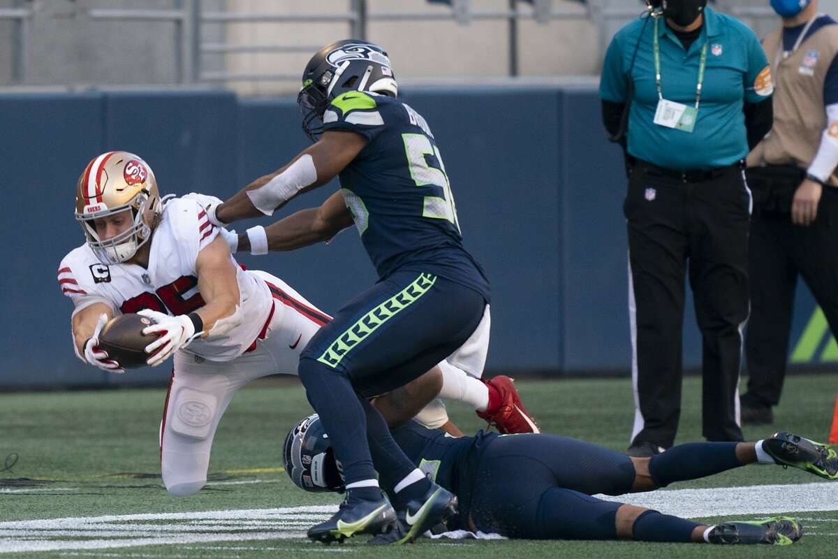 San Francisco 49ers tight end George Kittle dives for extra yardage as he is pushed out-of-bounds by Seattle Seahawks linebacker Jordyn Brooks an dcornerback Quinton Dunbar during the second half of an NFL football game, Sunday, Nov. 1, 2020, in Seattle. The Seahawks won 37-27. (AP Photo/Stephen Brashear)