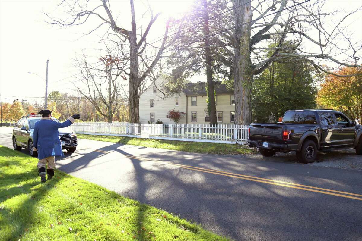 Todd Raker of Darien guides cars into the Mather Homestead Halloween drive-through on Saturday, Oct. 31.