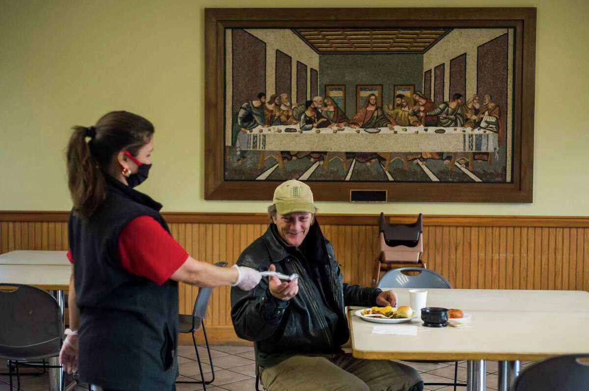 Victoria Bantau, left, hands silverware to John Schroeder, right, as Midland's Open Door reopens its dining hall for their daily soup kitchen service Monday in Midland. Hot meals are still being offered to-go from the front porch as well. (Katy Kildee/kkildee@mdn.net)