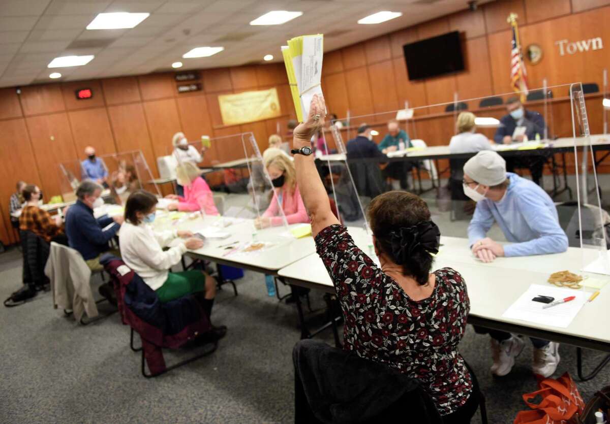 Byram's Laura Manganiello holds up a stack of ballots as poll workers prepare absentee ballots to be counted on Election Day at Town Hall in Greenwich, Conn. Monday, Nov. 2, 2020. On Monday, the outer envelopes of appoximately 15,000 absentee ballots were opened and envelopes were checked that they meet all the requirements to be officially counted on Election Day Tuesday.