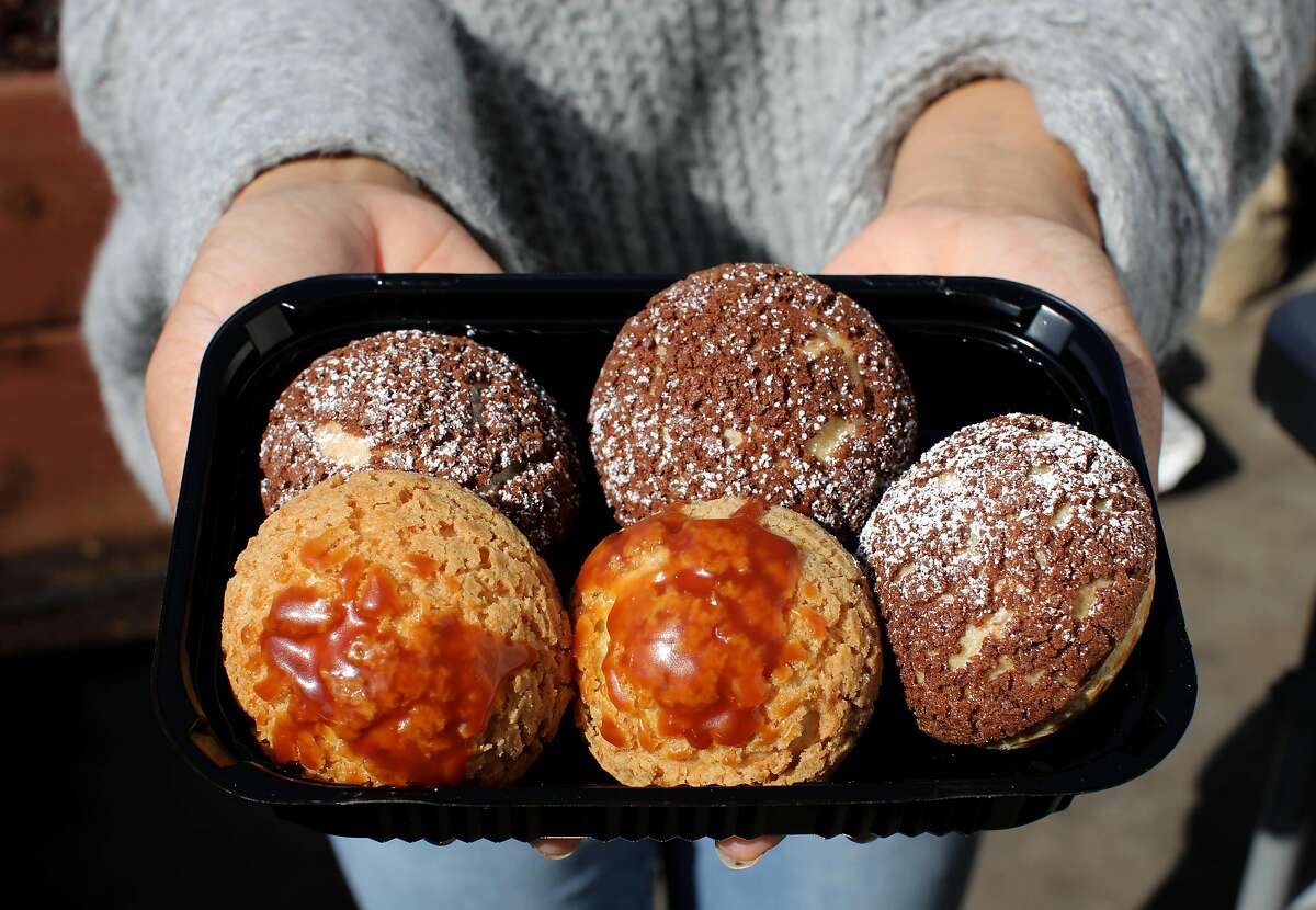 Thuy Nguyen of Thuy’s Treats shows her tray of choux au craquelin, cream puffs featuring salted caramel and chocolate peanut butter flavors, at Magnolia Mini Mart in Oakland. The specialty foods store is one example of an innovative food hub prioritizing collaboration during the pandemic.