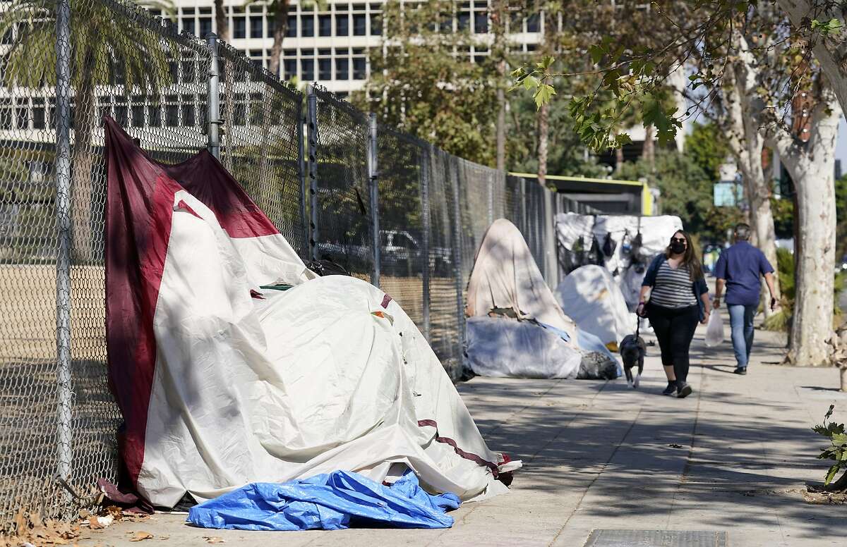 Pedestrians walk past a homeless encampment in downtown Los Angeles. The city is drafting an ordinance that would greatly restrict where homeless people may camp in public places — rules that opponents say would criminalize homelessness.
