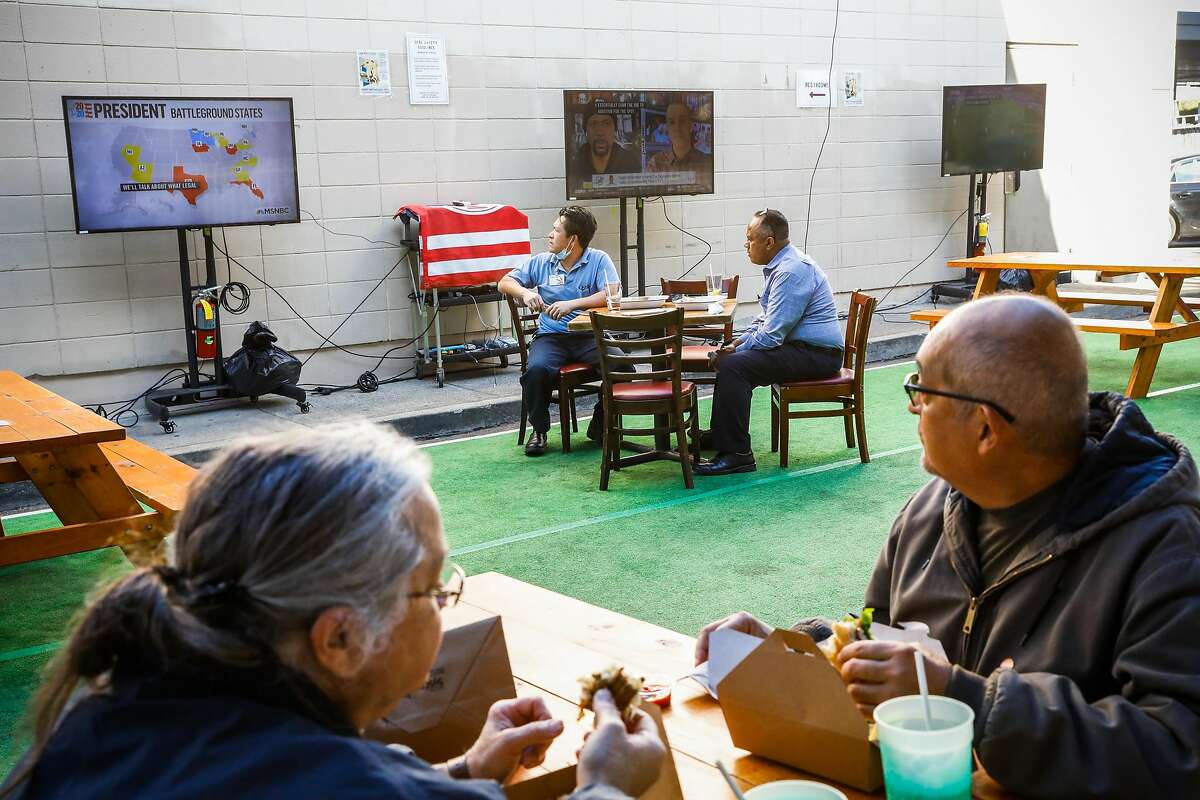 Diners watch election coverage on television as they eat outdoors at the San Francisco Athletic Club on Wednesday, Nov. 4, 2020 in San Francisco, California.