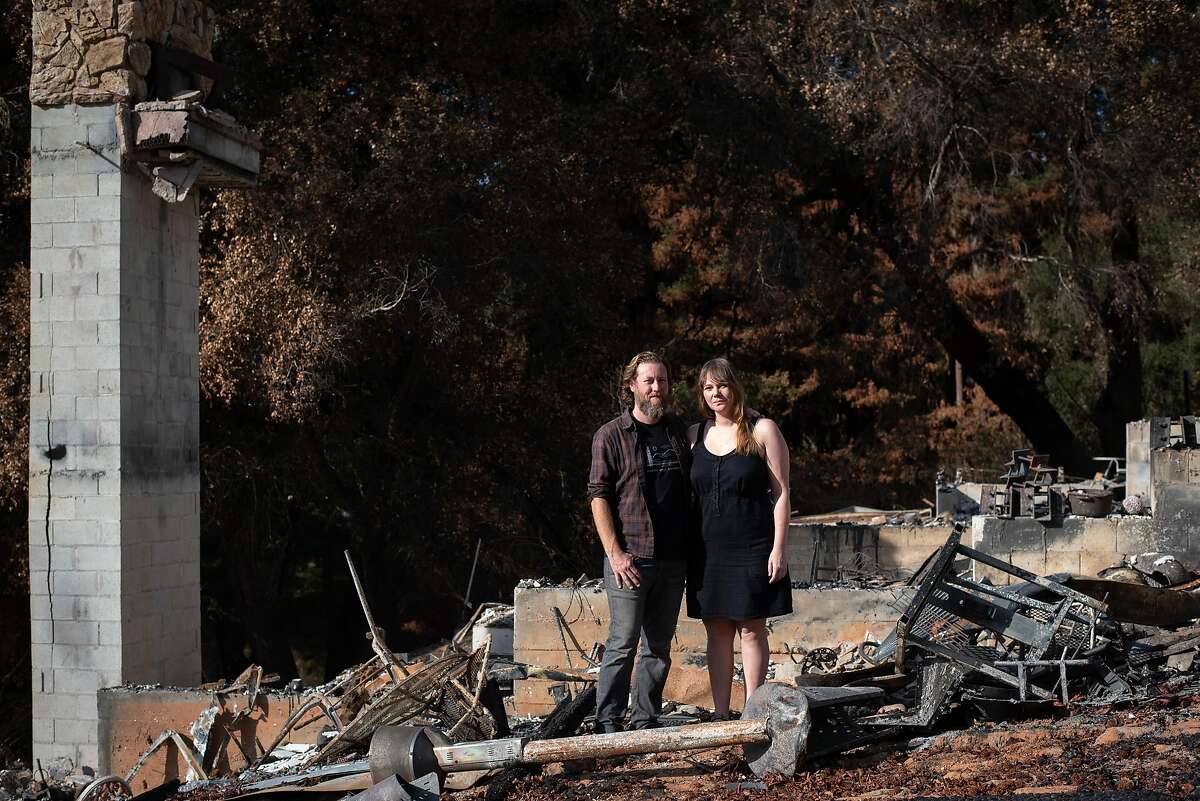 Jon Payne and his wife Elizabeth pose in front of the remains of their house in the Santa Cruz mountains. The Paynes had just finished work on a home recording studio when the CZU Lightning Complex Fire swept through and destroyed the house.